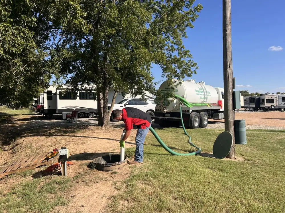 Diamond E crew member pumping a septic tank at an RV park, vacuum truck parked behind